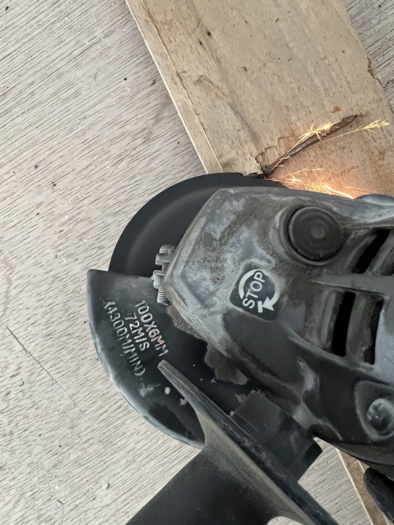 床材から出た釘をグラインダーで切り取っている様子